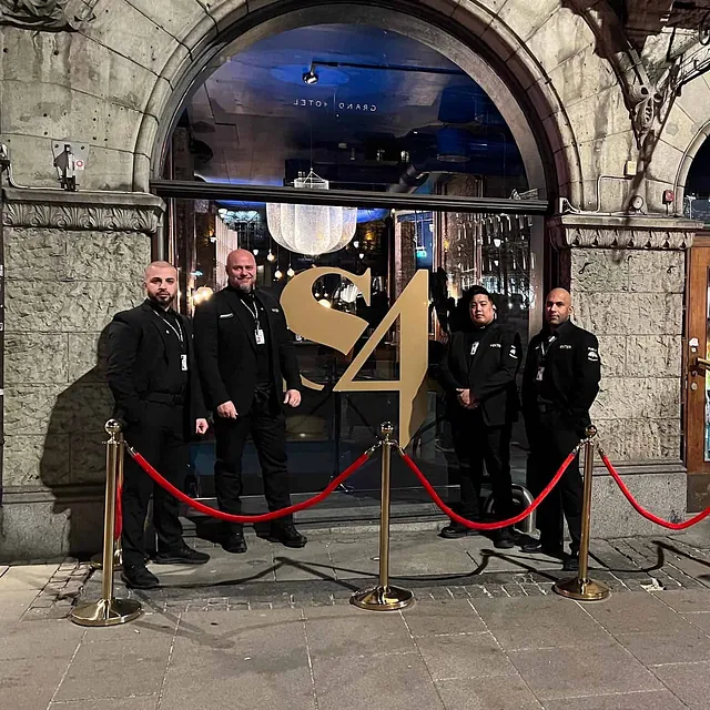 Fire vektere står foran en nattklubbinngang